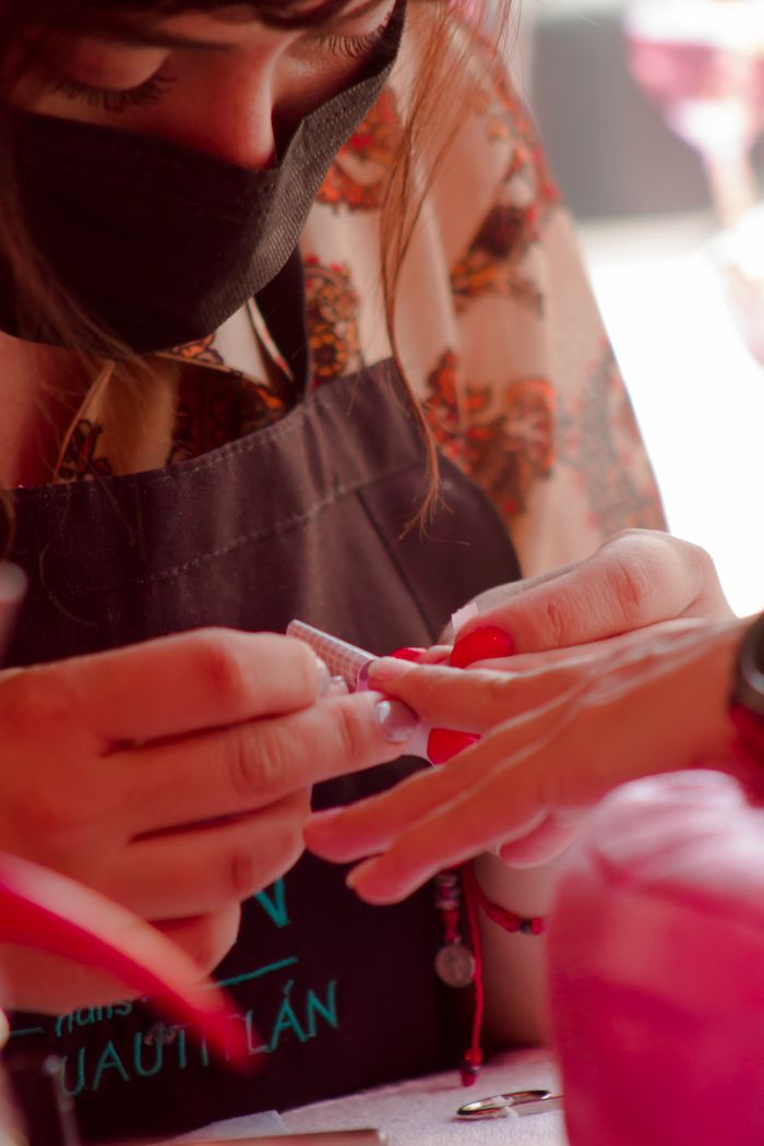 Beautician carefully applying nail extensions in a salon.